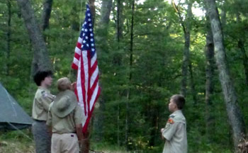 Raising the American flag at a campsite.